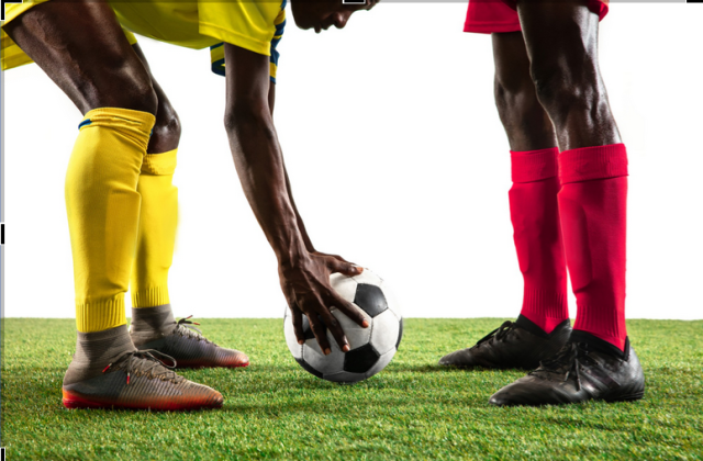 Soccer players placing ball on grass before kickoff